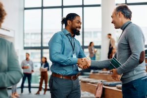 Happy businessmen greeting while attending an education event at conference hall.